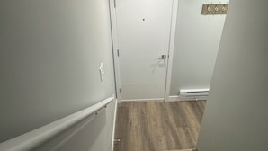 A staircase with wooden steps leading to a white door. - 2-Bedrooms | On site Parking | near YQR Airport (Regina)