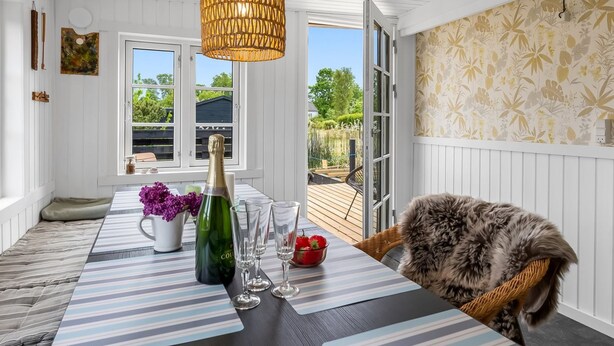 A dining area with a table set for two, a bottle of champagne, and a wicker chair. - "Blomma" - 1km from the sea by Interhome (Ebeltoft)