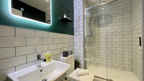 A modern bathroom with a white sink, mirror, and shower. - Stay Angels - Cosy Boho Apartment (Sheffield)