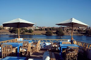 Enjoy al fresco dining with a view of the river and distant town from the boat's outdoor dining area.