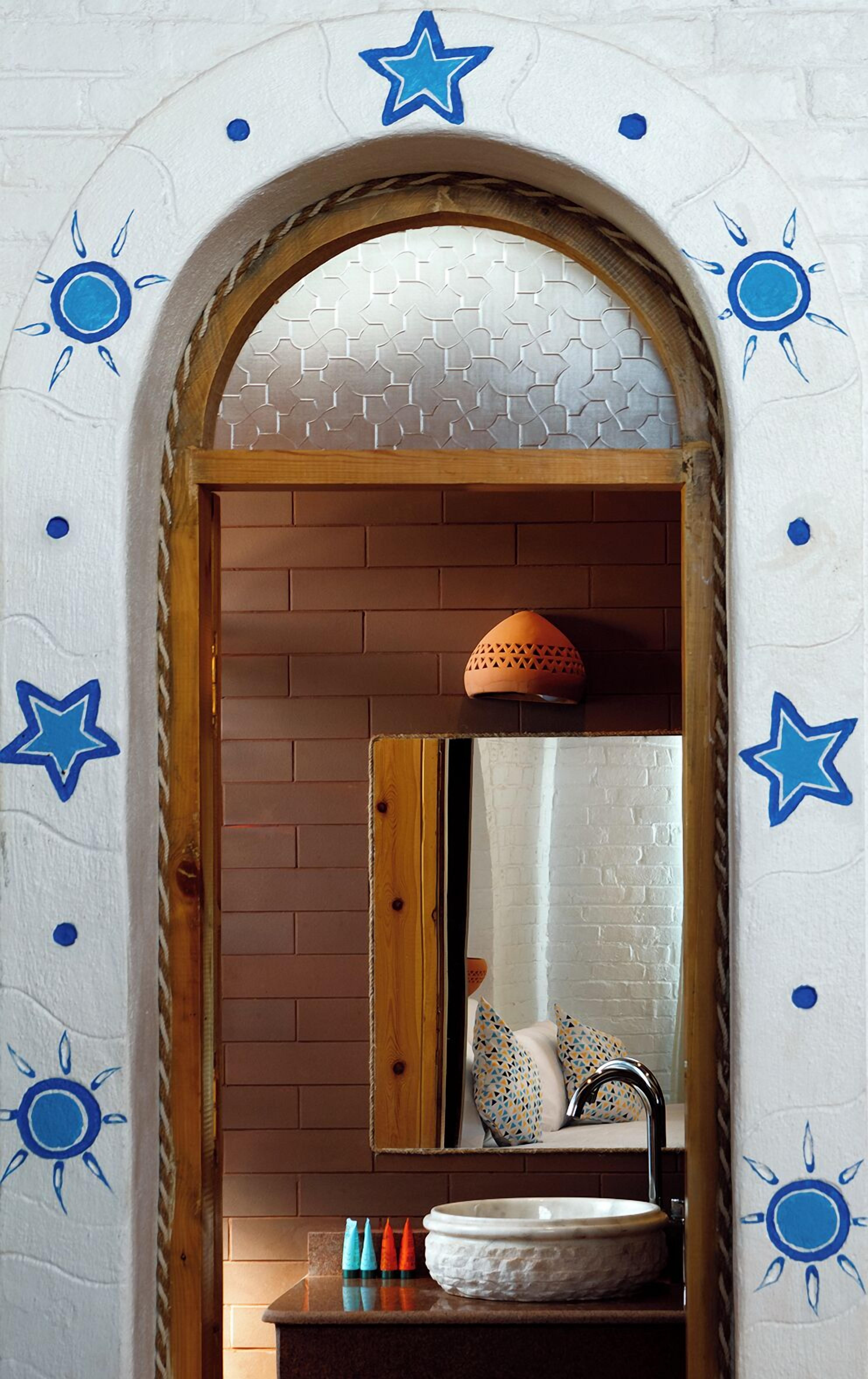 A bathroom with a wooden-framed mirror, a white sink, and decorative blue stars and suns on the walls.