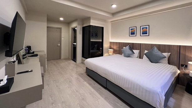 Ein modernes Hotelzimmer mit einem großen Bett, einem Fernseher, einem Schreibtisch und einem Kleiderschrank.