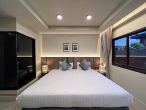 A modern hotel room with a large bed, two bedside lamps, a headboard with a wooden panel, and two framed pictures on the wall. - Karon Boutique (Karon)