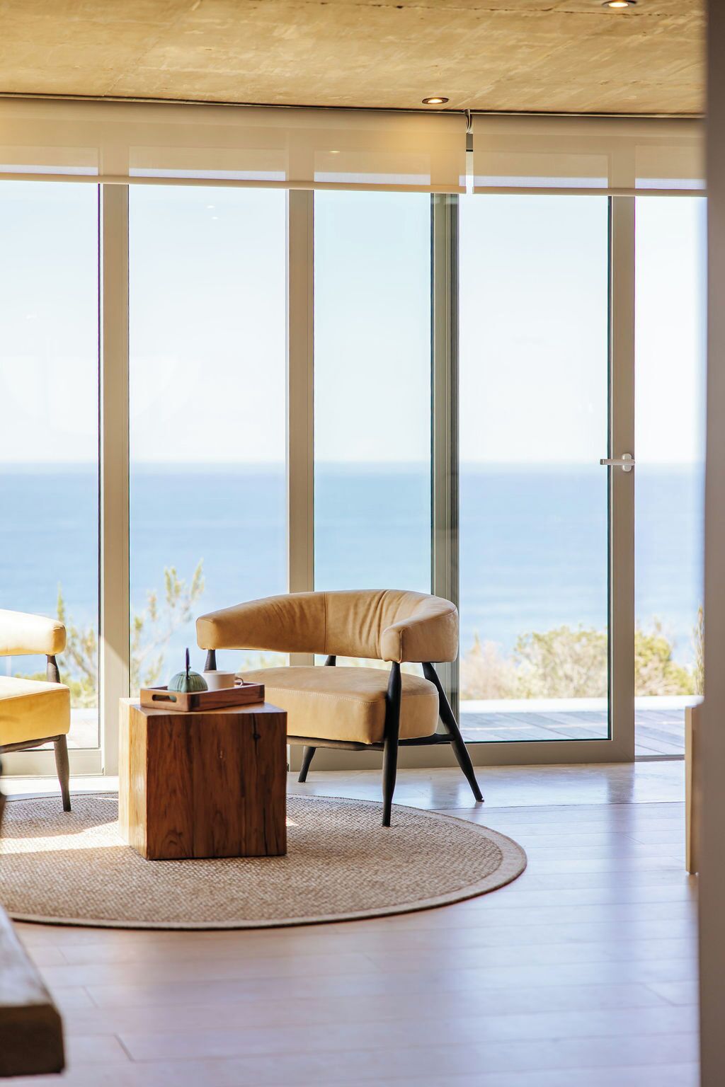 A modern living room with a large glass door leading to a balcony overlooking the sea.