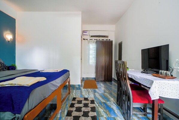 Une chambre à coucher comprenant un lit, un bureau, une télévision et un appareil de climatisation.