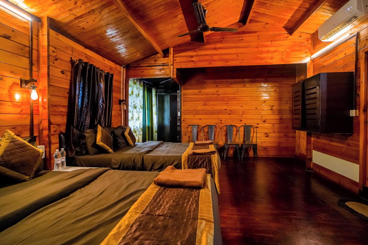 Een houten hut met twee bedden, een plafondventilator en een televisie.