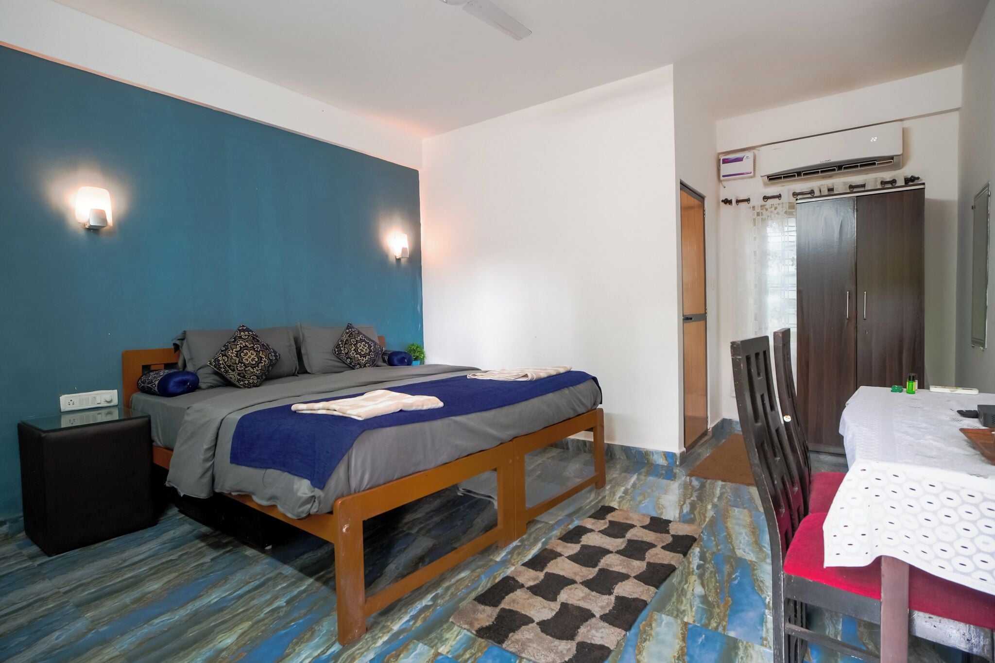 A bedroom with a bed, bedside table, and a table with chairs.