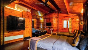 En stuga byggd av timmer med en säng, en soffa, en TV och en luftkonditioneringsanläggning.
