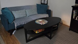 A living room with a grey sofa, a black coffee table, and a patterned rug. There are three paintings on the wall, a black TV stand, and a wooden floor. - 6 blocks to Santa Monica beach, great neighborhood  (Santa Monica)