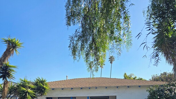 A house with a tiled roof, a porch with blue railings, and a front yard with potted plants and outdoor furniture. - 6 blocks to Santa Monica beach, great neighborhood  (Santa Monica)