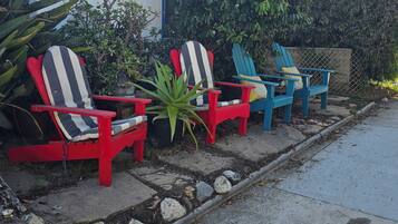 Outdoor seating with chairs and a table, a building with a blue door, and a palm tree.