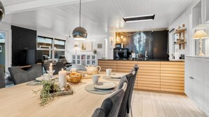 A modern kitchen with a central island, wooden cabinets, and a dining area with a table set for four.