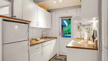 Eine moderne Küche mit weißen Schränken, einer Holzausziehtheke, einem eingebauten Backofen und einem Fenster mit Blick auf Grünflächen.