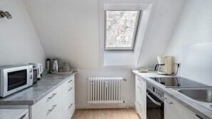 Eine moderne Küche mit Einbauofen, Mikrowelle und Kaffeemaschine, einem Fenster mit Aussicht und einem weißen Heizkörper.
