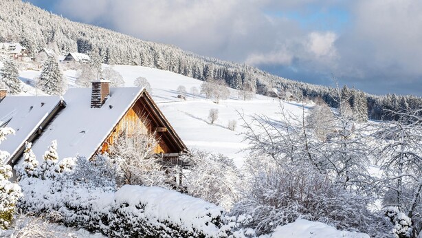 A wooden cabin with a sloped roof, surrounded by snow-covered trees and a hilly landscape. - Apartment '4, 65 Qm' with Shared Garden, Balcony and Wi-Fi (Lenzkirch)