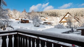 Ein verschneites Dorf mit Holzhäusern und blauem Himmel.