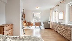 Ein Schlafzimmer mit einem Holzkasten, einem Bett mit einer Steppdecke, einem Fenster mit Blick, einem Stuhl und einer Heizung.
