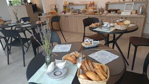 A dining area with tables set for breakfast, featuring bread, pastries, and a vase with flowers. - TENUTE LAZZARINO (Sciacca)