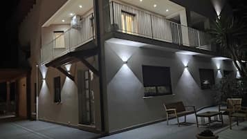 A two-story building with a balcony, outdoor seating, and a well-lit exterior.