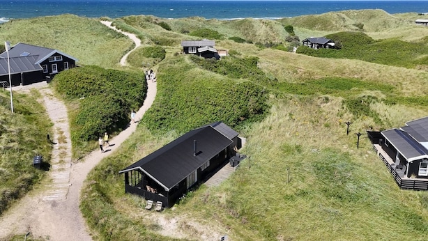 A coastal property with multiple buildings, a winding path, and a view of the sea.