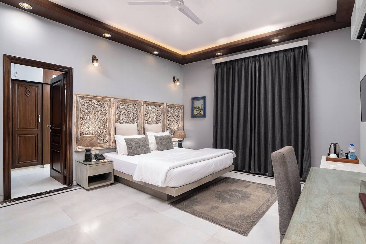 A modern bedroom with a bed, bedside tables, a desk, and a chair.