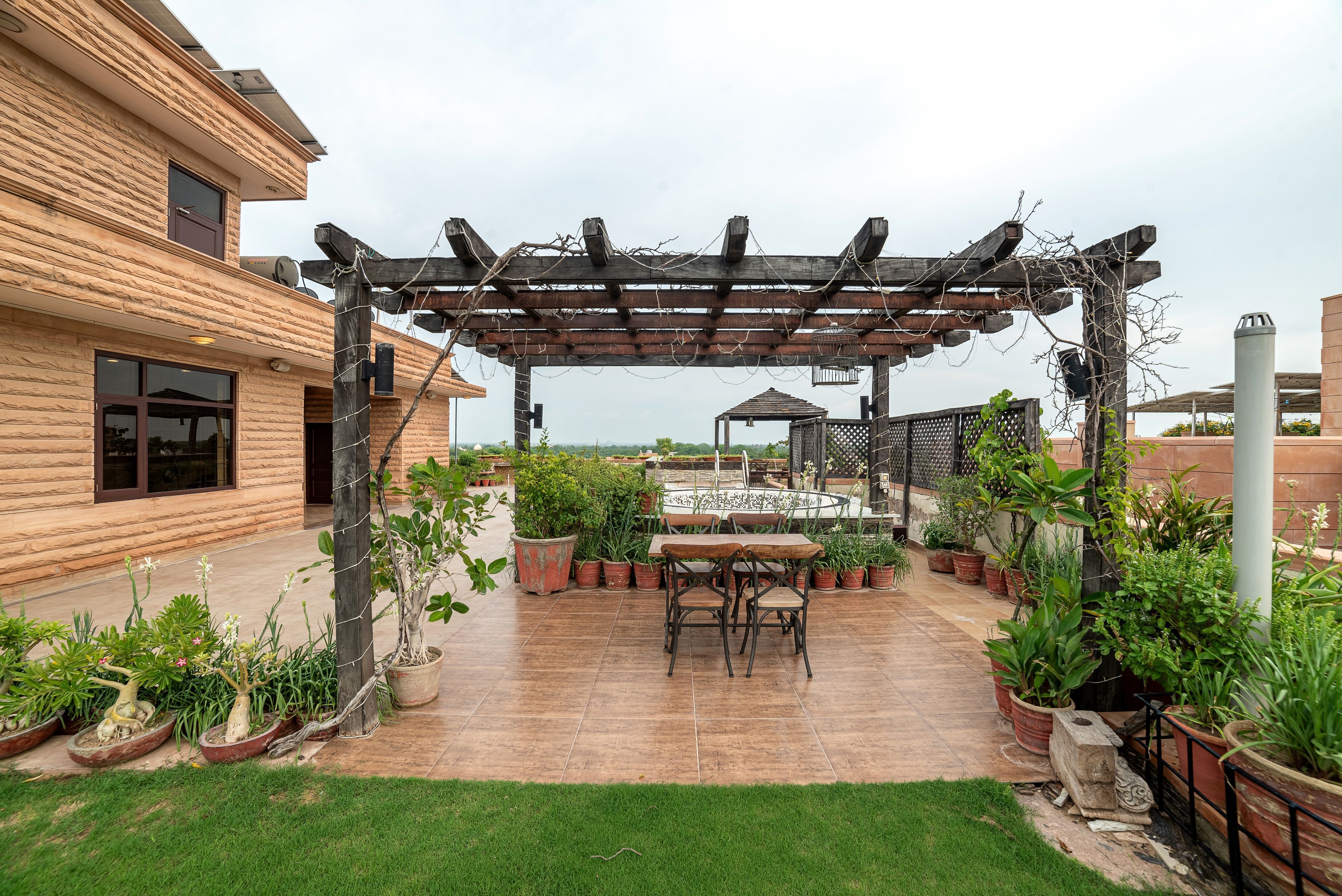 A patio area with a pergola, potted plants, and a table with chairs.