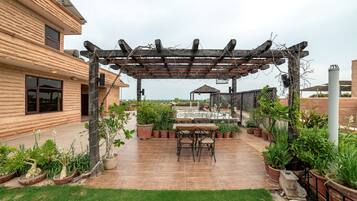 A patio area with a pergola, potted plants, and a table with chairs.