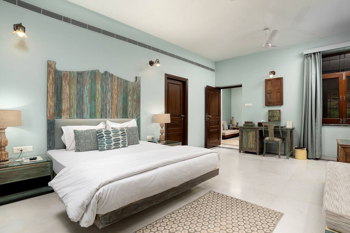 A bedroom with a large bed, bedside tables, a dresser, a chair, and a desk.