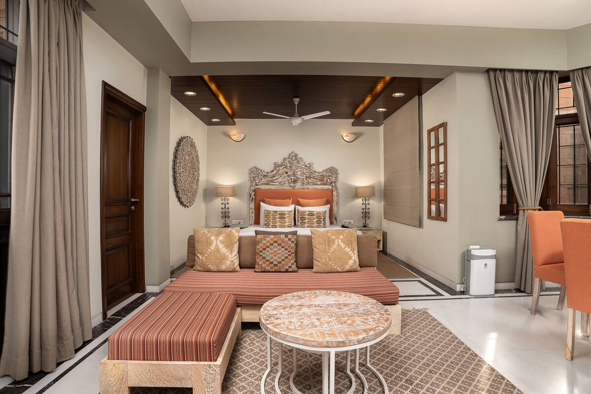 A modern bedroom with a large bed, a round table, and a sofa.