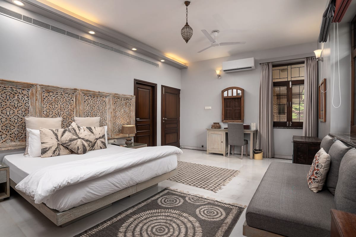 A bedroom with a bed, a desk, and a sofa.