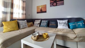 Ein gemütliches Wohnzimmer mit einem gestreiften Sofa, dekorativen Kissen und einem Couchtisch mit einer Kerze.
