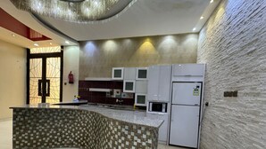 Une cuisine moderne dotée d’un îlot central aux lignes courbes, d’appareils électroménagers intégrés et d’un mur en pierre à texture.