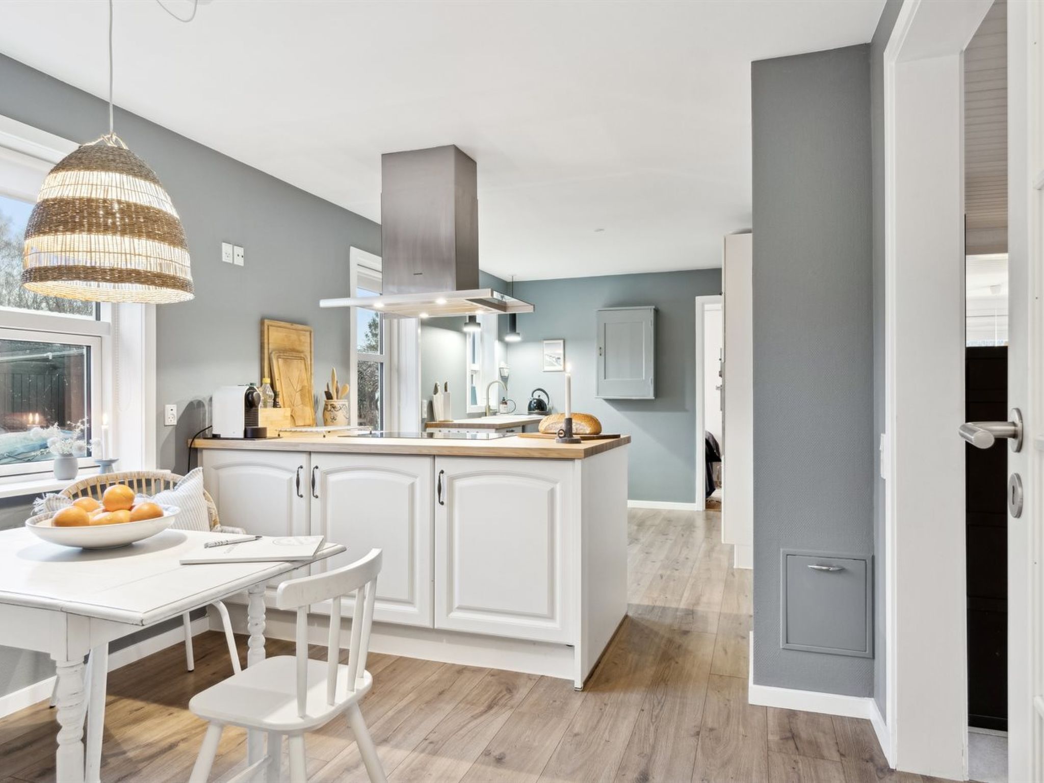 Une cuisine moderne avec des meubles blancs, un îlot central et un luminaire suspendu.