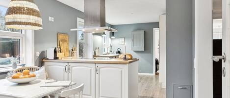 A modern kitchen with white cabinetry, a central island, and a hanging light fixture.