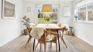 A dining area with a wooden table, wicker chairs, and a hanging light fixture. - "Nayeli" - 1.2km from the sea by Interhome (Vejby)