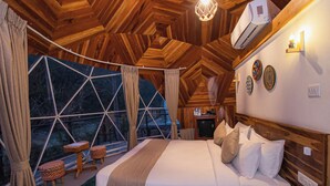 A cozy bedroom with a large bed, wooden headboard, and a view through a geometric window. - Harness Zipline And Adventure Resort (Godaam)