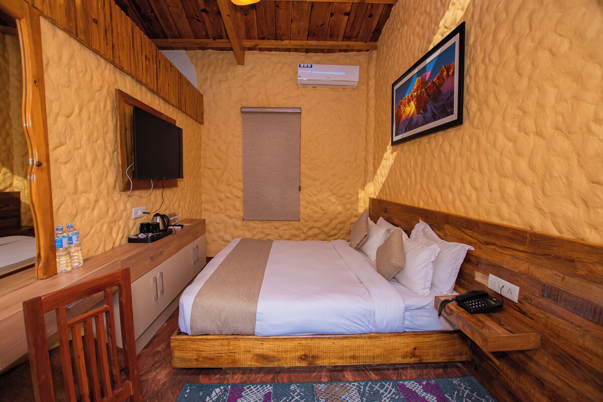 Ein gemütliches Zimmer mit einem hölzernen Bett, einem Schreibtisch, einem Fernseher und einer Klimaanlage.