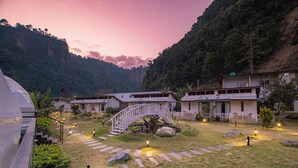 A resort with a central bridge, multiple buildings, and a mountainous backdrop. - Harness Zipline And Adventure Resort (Godaam)