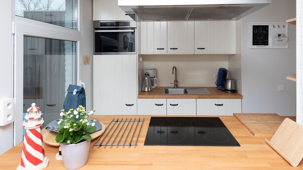 A modern kitchen with white cabinets, a black stove, and a coffee maker. - Horizon by the Sea by Interhome (Renesse)