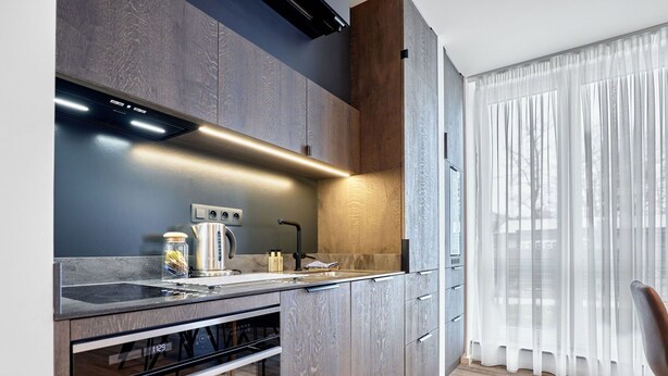 Een moderne keuken met donkerhouten kastjes, een roestvrijstalen afzuigkap en een inbouwoven.