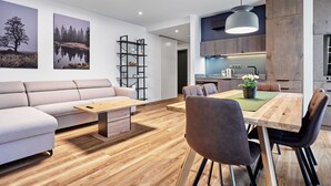 Een moderne woonkamer met een bank, salontafel en een eetgedeelte met stoelen en een tafel.