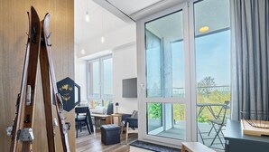 A modern living room with large windows, a wooden floor, a dining area, and a staircase leading to a balcony. - Lovely apartment for 6 people with WIFI, A/C, TV and balcony (Ostrov)