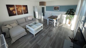 A modern living room with a sofa, coffee table, and dining table. There are world maps on the wall and a potted plant. - Beautiful condominium incl. secured parking space on the outskirts of Hoyerswerda (Hoyerswerda)