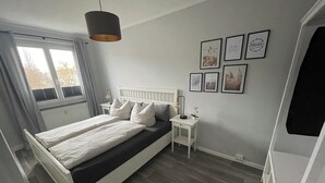 A bedroom with a bed, bedside tables, a hanging light fixture, and framed pictures on the wall. - Beautiful condominium incl. secured parking space on the outskirts of Hoyerswerda (Hoyerswerda)