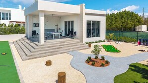 Une maison moderne dotée d’un patio couvert, d’une table de billard et d’un petit jardin.