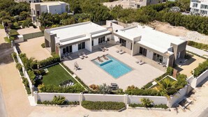 A modern residential complex with a central swimming pool, multiple lounge areas, and a well-maintained garden.