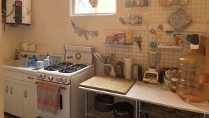 Una cucina con forno, lavello e diversi utensili da cucina su scaffali e piani di lavoro.