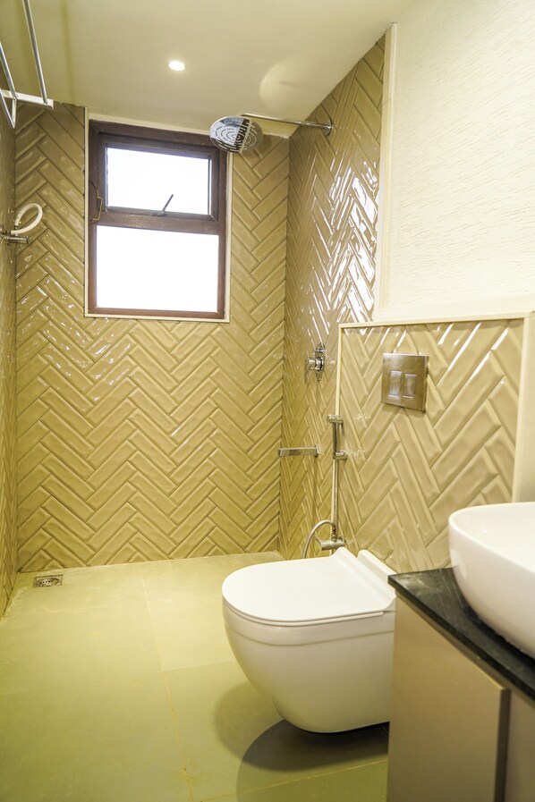 A bathroom with a herringbone tile pattern, a toilet, a sink, and a shower with a handheld showerhead.