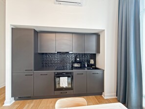 Eine moderne Küche mit dunklen Schränken, einer schwarzen Spritzschutzwand und einem eingebauten Backofen.
