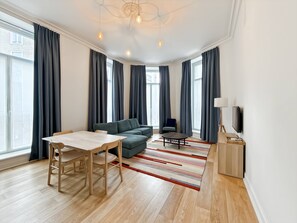 Ein modernes Wohnzimmer mit einer Couch, einem Esstisch und einem Fernseher.